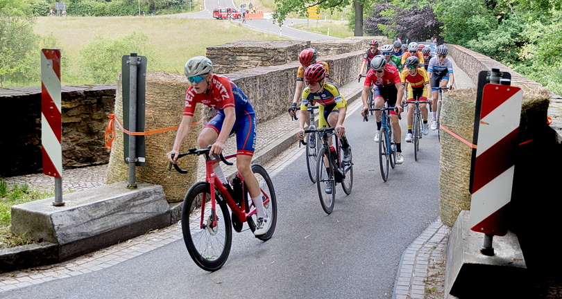Radrennfahrer auf einer schmalen Brücke