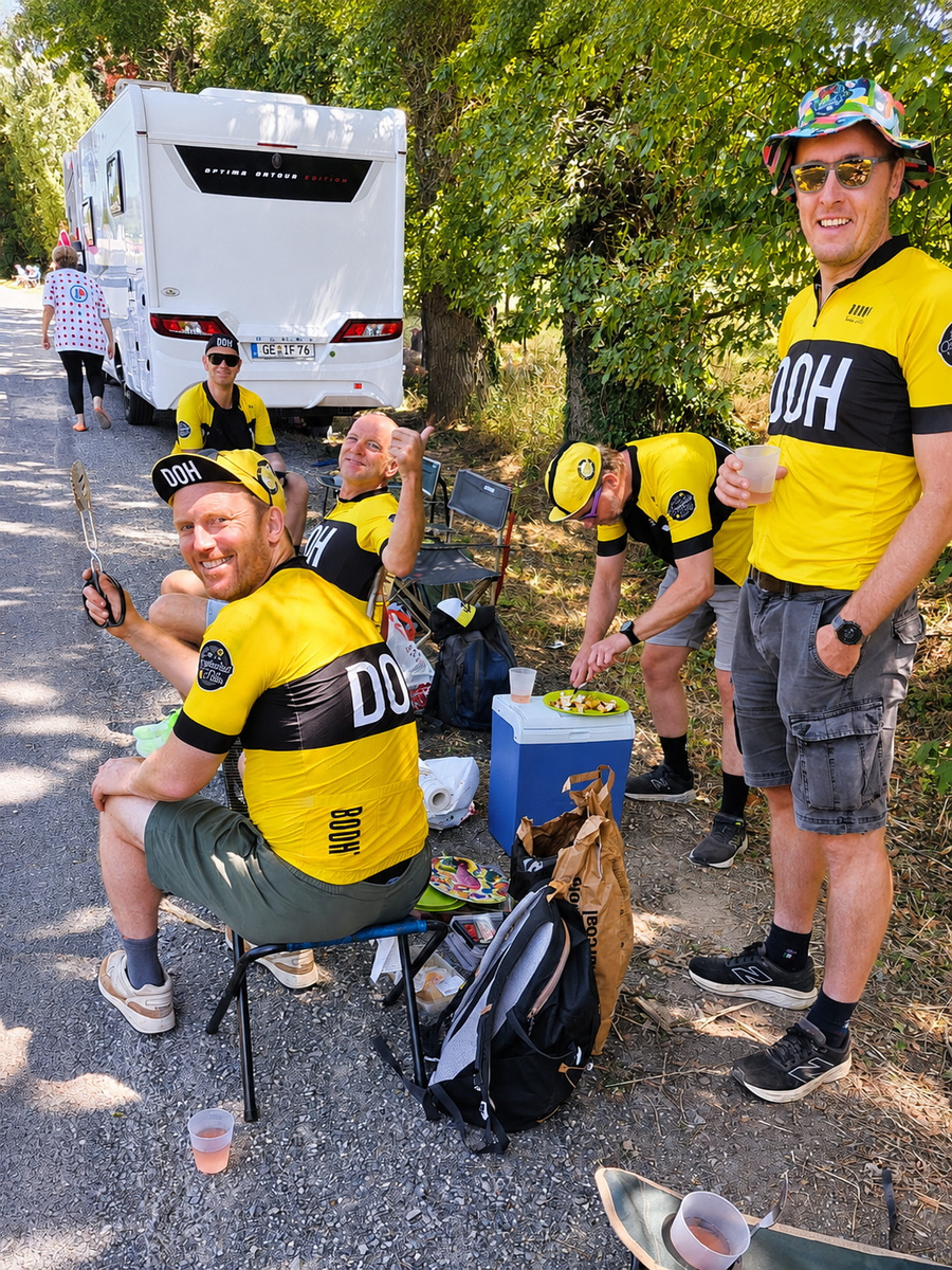 Gruppe von Fans in gelben Trikots feiert gemeinsam am Straßenrand