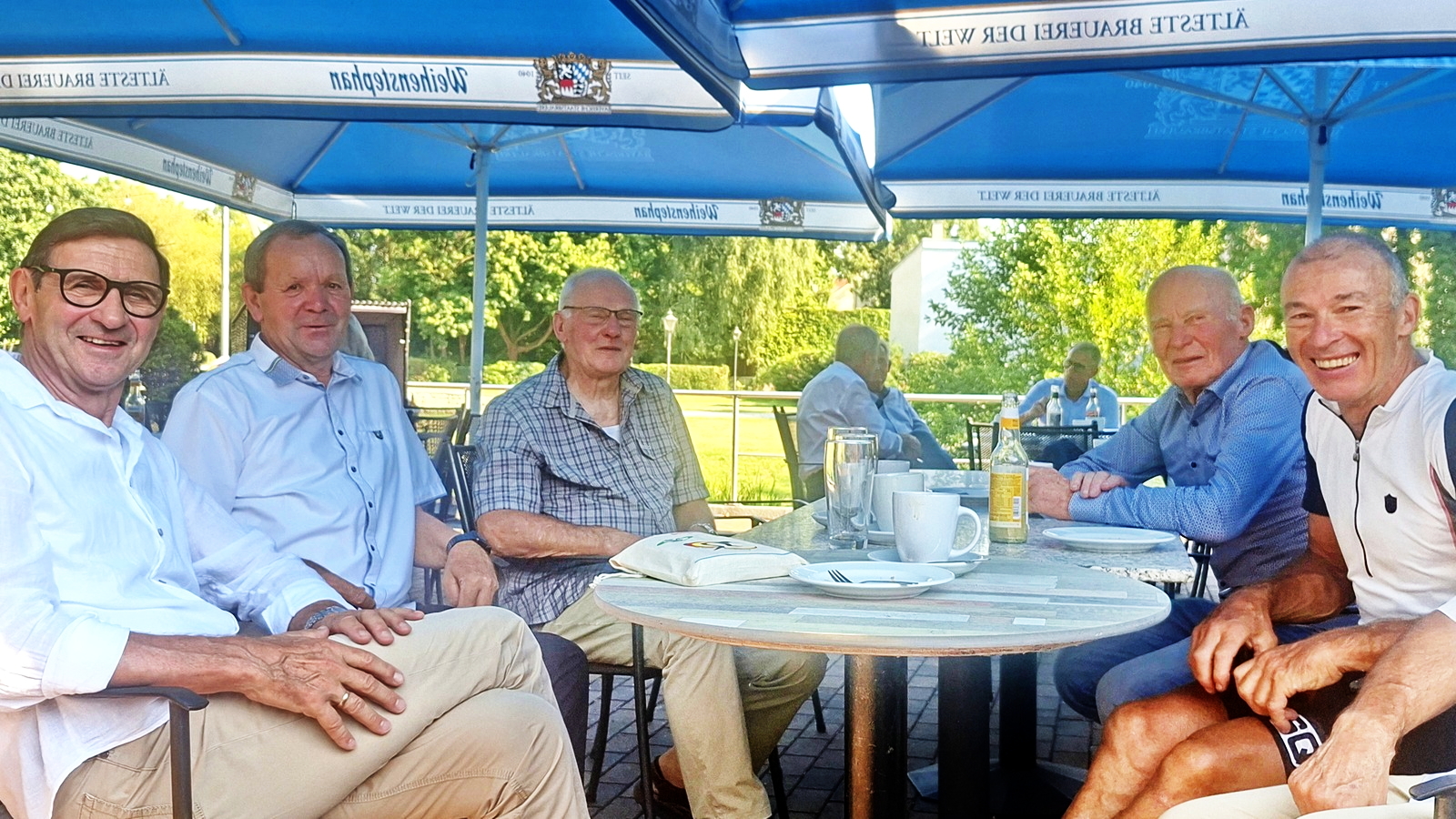 Gruppe ehemaliger Radsportler sitzt gemeinsam an einem Tisch im Freien