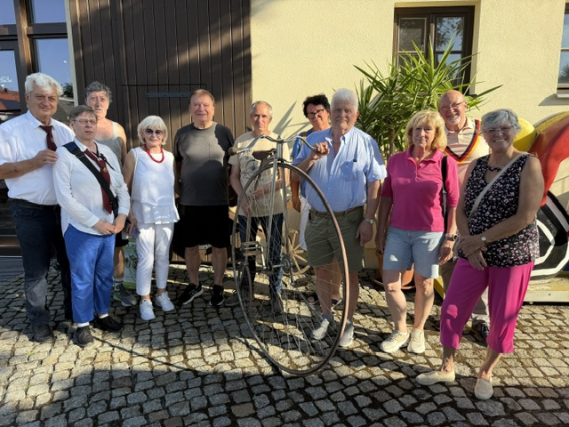Mitglieder der Bundes-Ehren-Gilde stehen gemeinsam mit einem historischen Hochrad vor dem Velocium